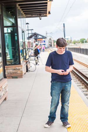 Teenage boy at the lightrail station in urban area.の写真素材