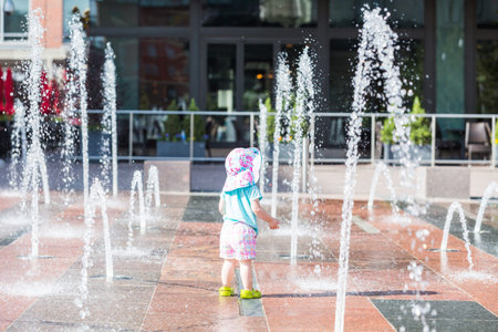 Cute toddler girl playing with small fountains in splash park.の写真素材
