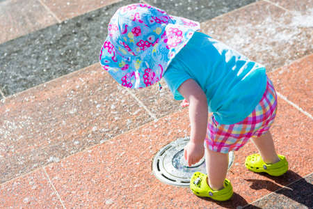Cute toddler girl playing with small fountains in splash park.の写真素材