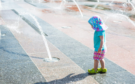 Cute toddler girl playing with small fountains in splash park.の写真素材