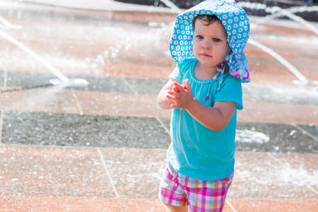 Cute toddler girl playing with small fountains in splash park.の写真素材
