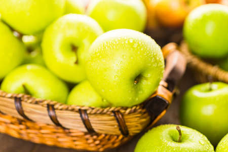 Variety of organic apples in baskets on wood table.の写真素材