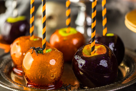 Table with colored candy apples and cake for Halloween party.の写真素材
