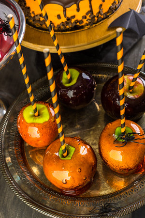 Table with colored candy apples and cake for Halloween party.の写真素材