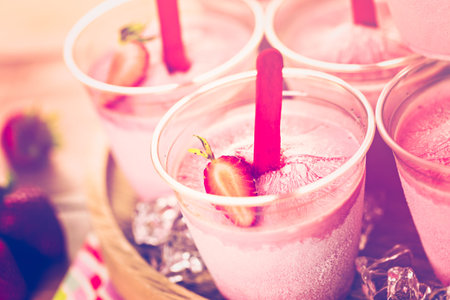 Homemade strawberry ice made in plastic cups.