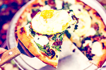 Fresh breakfast pizza with three farm fresh eggs in Italian restaurant.の写真素材