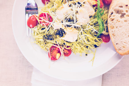 Homemade angel hair pasta with pesto sauce, roasted cherry tomatoes and grilled chicken.