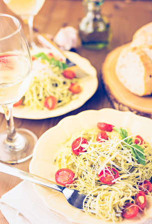 Homemade angel hair pasta with pesto sauce and roasted cherry tomatoes.の写真素材