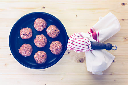 Frying large homemade Italian meatballs on a midium frying pan for dinner.の写真素材