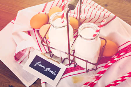 Fresh farm milk in glass jars and eggs on wood tableの写真素材