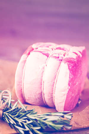 Organic pork lion roast with rosemary on wood farm table.の写真素材