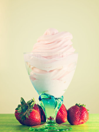 Cup of strawberry frozen yogurt or soft serve ice cream with fresh fruit.