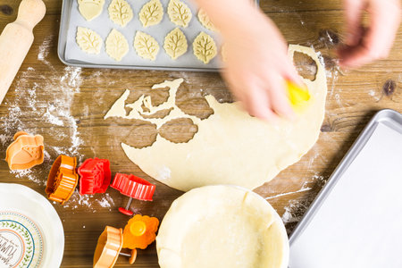 Cutting out Autumn leafs with cookie stamper to decorate pumpkin pie.