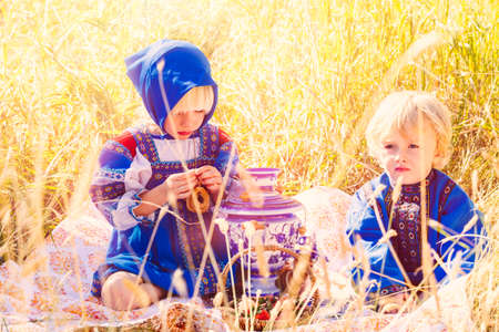 Russian children in traditional Russian costumes playing in the forest.の写真素材