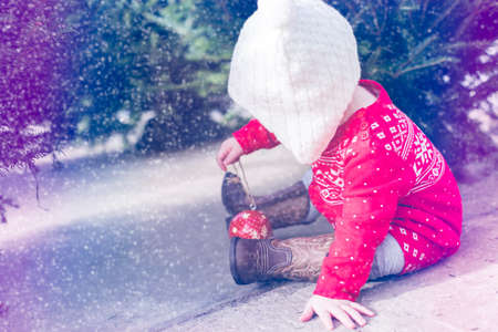 Cute baby girl in red Scandinavian dress at the Christmas tree farm.の写真素材