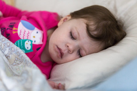 Baby girl sleeping in her parents bed.の写真素材