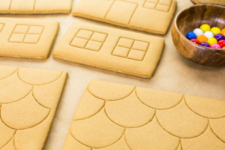Decorating gingerbread house with royal icing and colorful candies.