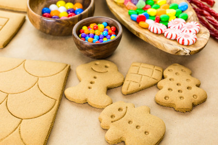 Decorating gingerbread house with royal icing and colorful candies.