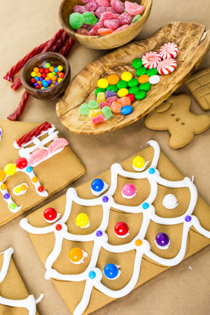 Decorating gingerbread house with royal icing and colorful candies.