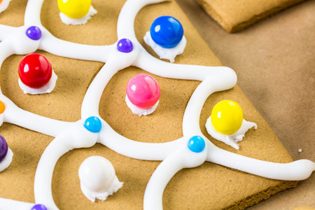 Decorating gingerbread house with royal icing and colorful candies.