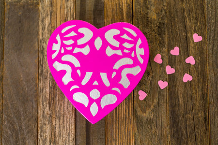 Chocolates in heart shaped box on rustic wood table.