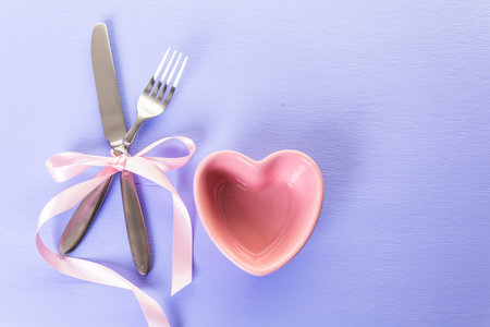 Utencils with pink ribbon on blue background.