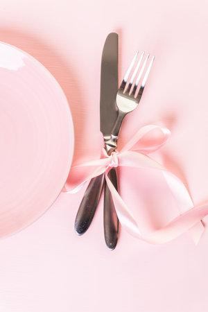 Utencils with pink ribbon on pink background.の写真素材