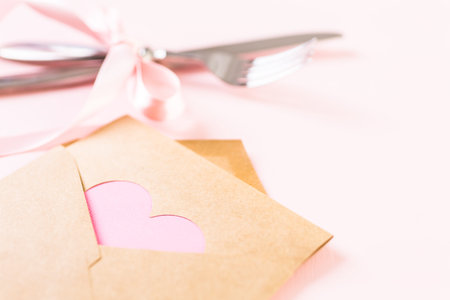 Utencils with pink ribbon on pink background.
