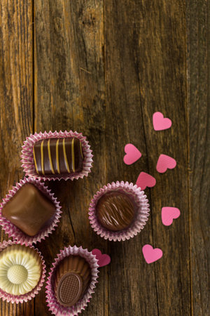 Assorted chocolates on rustic wood table.