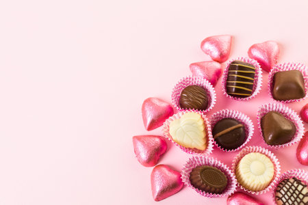 Assorted chocolates on pink background.