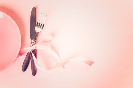 Utencils with pink ribbon on pink background.の写真素材