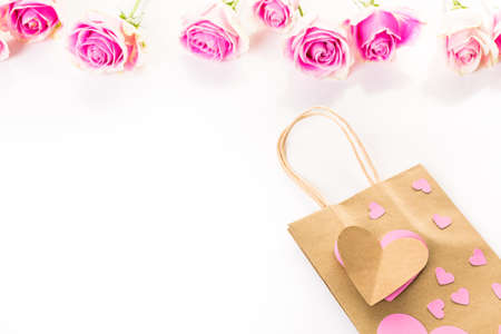 Pink roses and hand crafted gift bag on a white background.の写真素材
