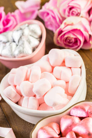 Pink roses with chocolates on rustic wood table.の写真素材