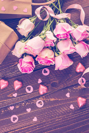 Pink roses and gift wrapped in recycled paper on rustic wood table.の写真素材