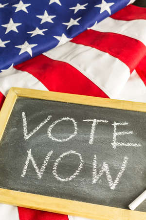 Vote sign on chalk board next to the American Flag.の写真素材