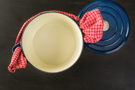 Enameled blue cast iron covered dutch oven on black wood table.