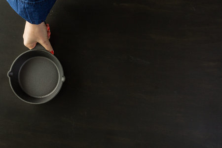 Traditional cast iron skillet on black wood table.