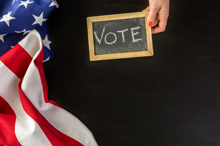 Vote sign on chalk board next to the American Flag.