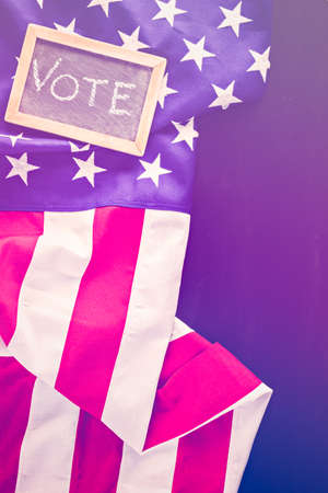 Vote sign on chalk board next to the American Flag.の写真素材