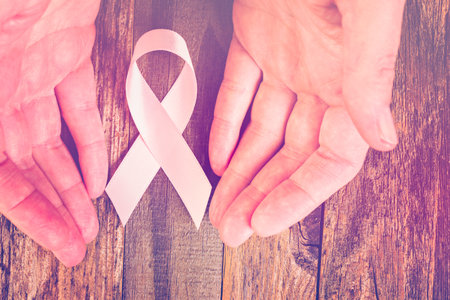 Womens health symbol in pink ribbon on wooden board.