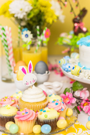 Dessert table set with cake and cupcakes for Easter brunch.