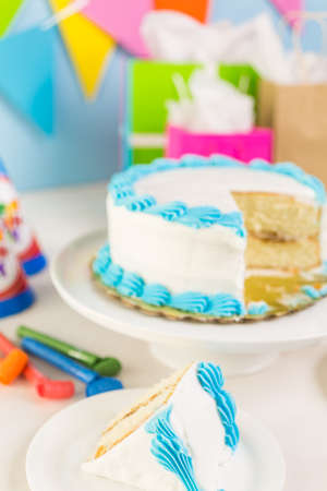 Simple white Birthday cake slice with white and blue icing.の写真素材