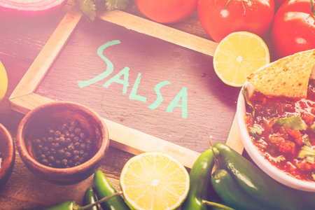 Fresh salsa in white bowl with ingredients.