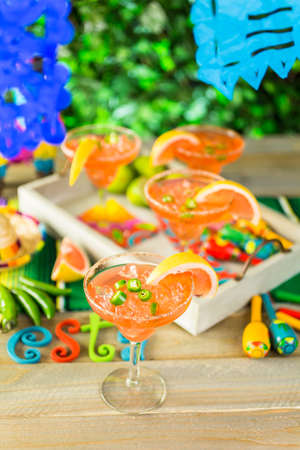 Spicy grapefruit margarita on ice in margarita glasses on the table in the garden.の写真素材