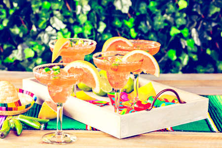 Spicy grapefruit margarita on ice in margarita glasses on the table in the garden.の写真素材