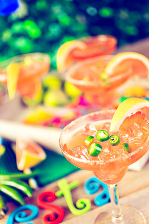 Spicy grapefruit margarita on ice in margarita glasses on the table in the garden.の写真素材