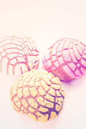 Homemade pan dulche with white, yellow, and pink icing.の写真素材