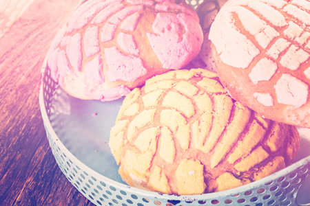 Homemade pan dulche with white, yellow, and pink icing.
