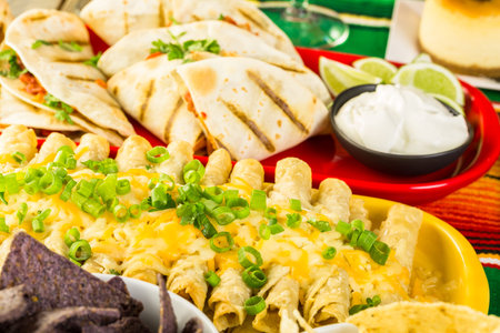 Fiesta party buffet table with chicken taquitos and other traditional Mexican food.