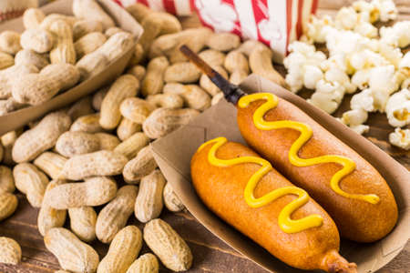 Game day traditional snacks included corndogs and salted peanuts on a wood board.の写真素材